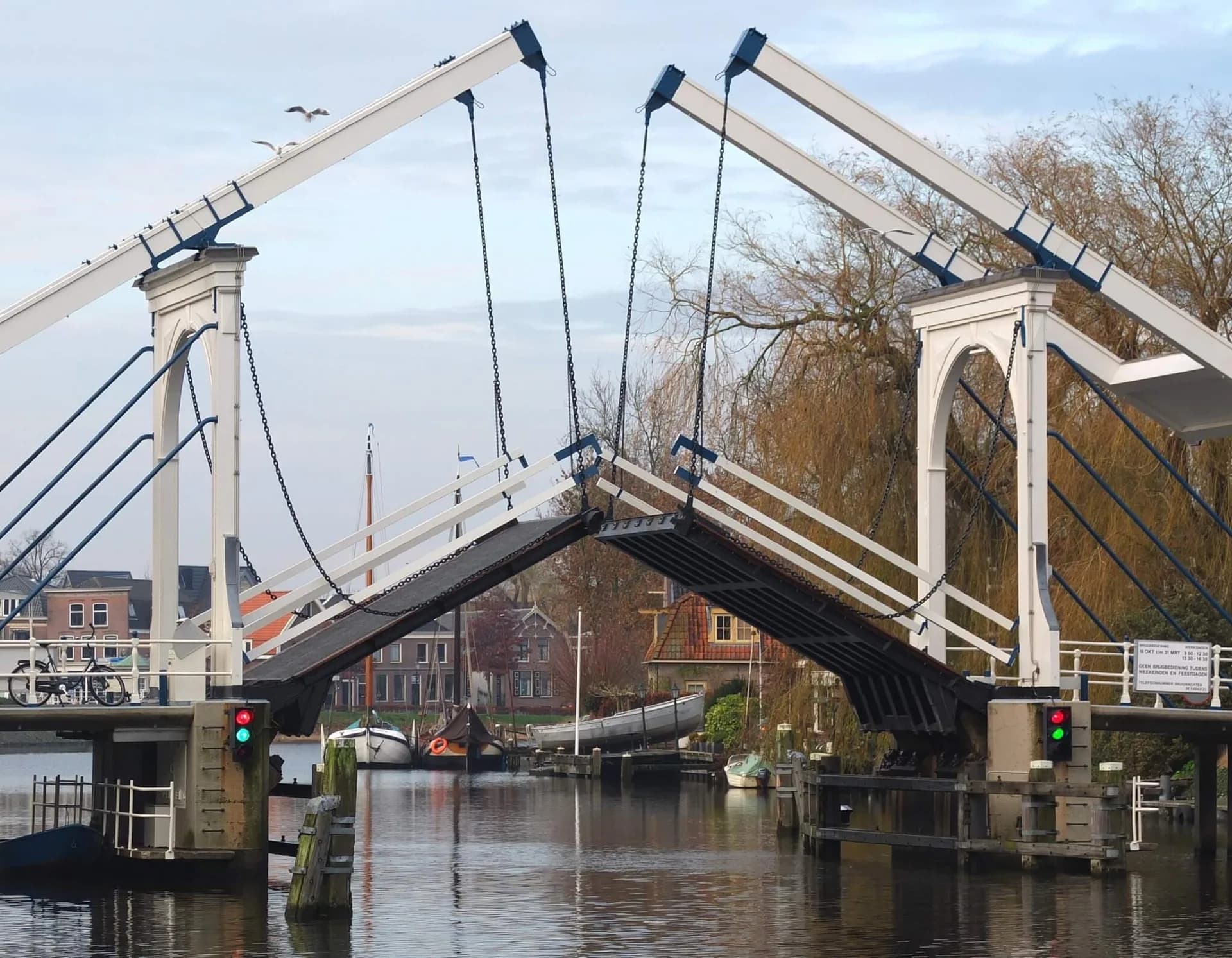 Geopende ophaalbrug over een vaarweg, met rood en groen doorvaartlicht